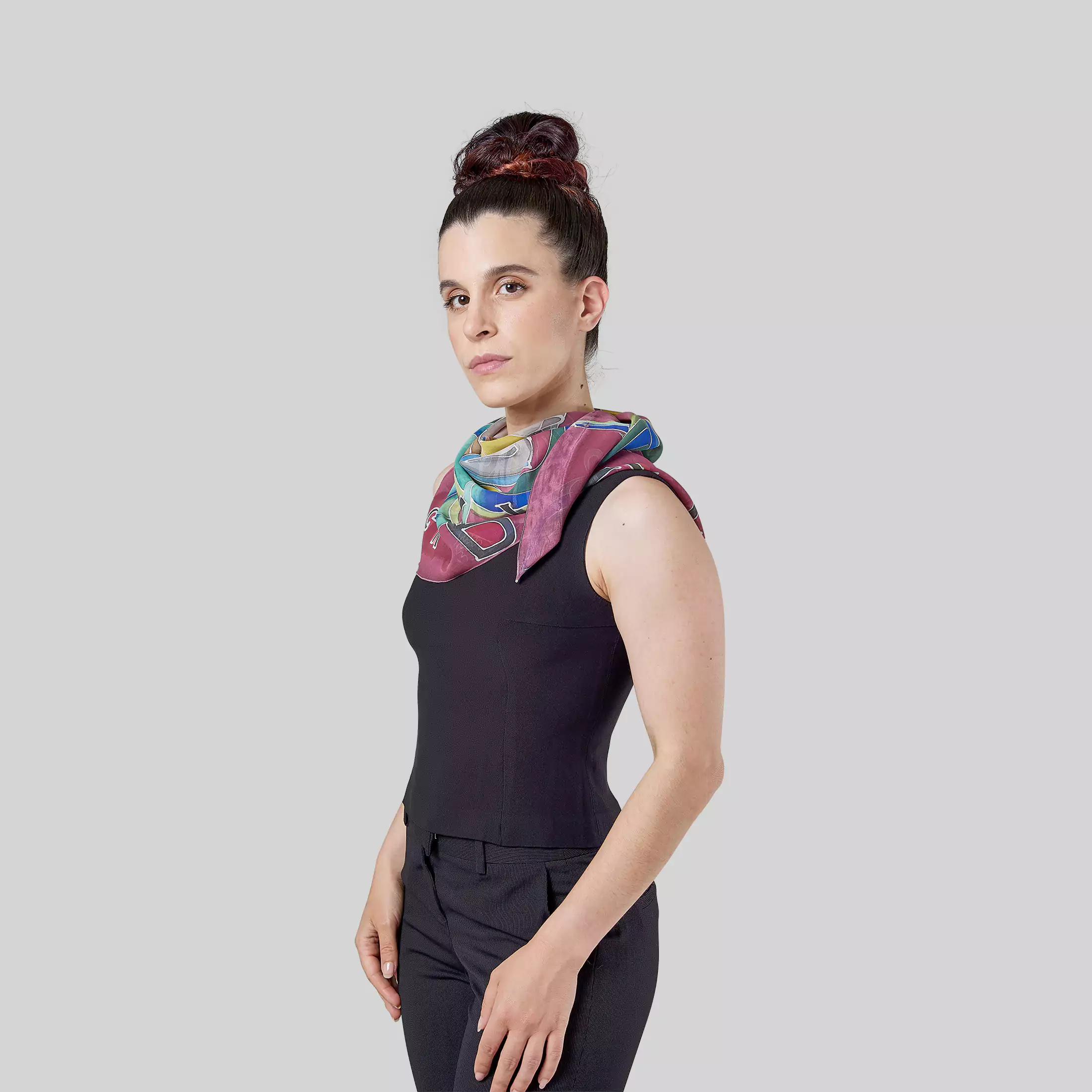 Una modella fotografata di profilo indossa al collo il foulard da donna in georgette di seta dipinta a mano "Rigoletto" di Fosca's Batik